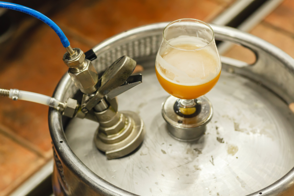 A Keg with clean gas beer gas lines and a glass of fresh beer